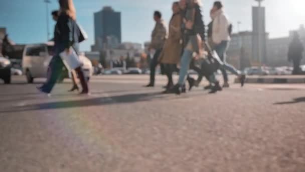 Rozostřený objektiv, rozostřený. Po ulici kráčí dav chodců, na pozadí velkého města. Lidé chodí za slunečného dne. Život ve městě. Zpomalený pohyb — Stock video