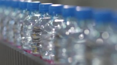 Yakın plan. Plastik su şişeleriyle konveyör hattı. Endüstriyel ekipman Şişelenmiş su ve içecek fabrikası..