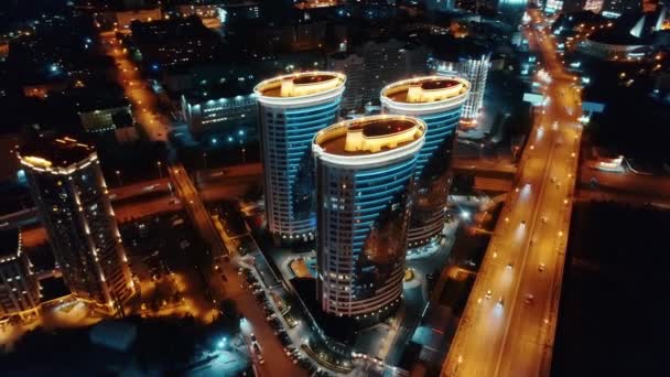 Vista superior de belos edifícios modernos da cidade à noite. Iluminação LED de edifícios. Estrada no centro da cidade. Luzes da cidade noturna. — Vídeo de Stock