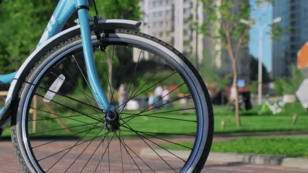 Novosibirsk, 15 de julho de 2019. Close-up de uma bicicleta. A rapariga entra na bicicleta e vai embora. Belo dia ensolarado de verão. Rodas de bicicleta, pedais. Sapatos desportivos. — Vídeo de Stock