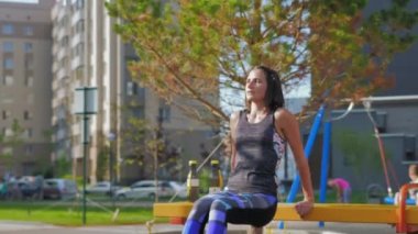 Novosibirsk, 20 Temmuz 2019. Genç, güzel esmer kadın spor için sokak simülatörlerine giriyor. Fitness ve sağlıklı yaşam tarzı, açık hava sporları, spor sahası. 