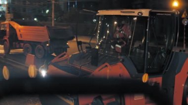 Novosibirsk bölgesi, 7 Eylül 2019. Bir yol silindiri, şehir ışıkları ve yol yapım ekipmanlarının zeminine asfalt serer. Gece şehirde yol tamiri.