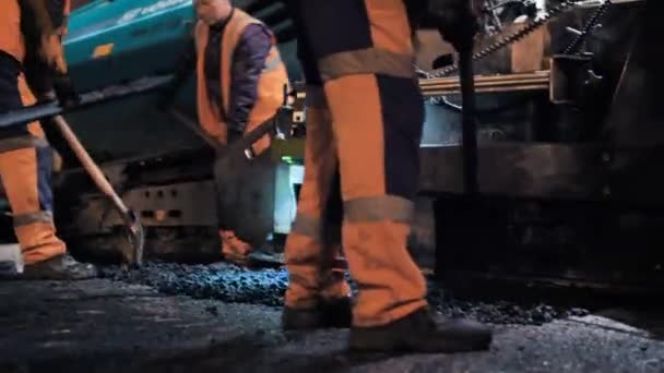 Novosibirská oblast, 7. září2019. Silniční dělníci rozvádějí asfaltovou směs před asfaltovým dlaždicem. Oprava městské silnice v noci. Stavba silnic. — Stock video
