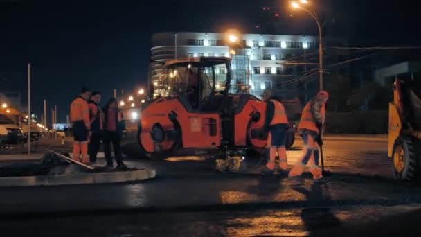 Novosibirsk bölgesi, 7 Eylül 2019. Yol işçileri asfalt karışımı dağıtır. Gece bir şehir yolunun tamiri. Yol silindiri asfalt seriyor.. — Stok video