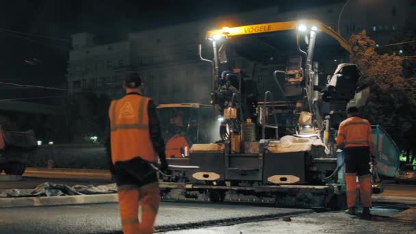 Obwód nowosybirski, 7 września 2019 r. asfalt brukarz pracy. Pracownicy dróg mierzą wysokość asfaltu. Naprawa drogi miejskiej w nocy. — Wideo stockowe