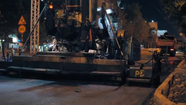 Novosibirsk região, 7 de setembro de 2019. Trabalhador rodoviário no painel de controle de pavers de asfalto. Reparação de estradas na cidade à noite. — Vídeo de Stock
