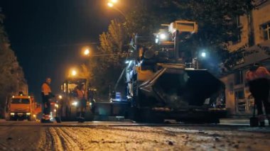 Novosibirsk bölgesi, 7 Eylül 2019. Gece şehirde yol tamiri, yol işçileri. Asfalt kaldırım işliyor, yol silindiri asfaltı seriyor..