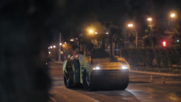 Novosibirsk, 7 de septiembre de 2019. Rodillo de carretera pone asfalto en la ciudad. Reparación de carreteras por la noche. Construcción de una nueva carretera. Movimiento lento — Vídeos de Stock