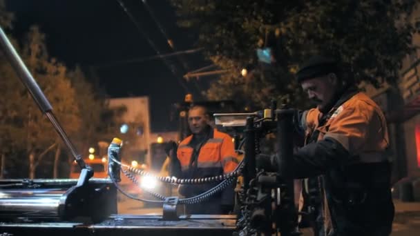 Περιοχή Νοβοσιμπίρσκ, 7 Σεπτεμβρίου 2019. Ένας εργάτης οδοποιίας προσαρμόζει και προσαρμόζει τον τελειωτή paver. Επισκευή αστικού δρόμου τη νύχτα. — Αρχείο Βίντεο