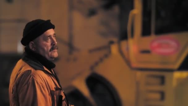 Novosibirsk regio, 7 september 2019. Een wegenwerker controleert het arbeidsproces. Weg reparatie in de nachtstad. Op de achtergrond legt een wals asfalt. — Stockvideo