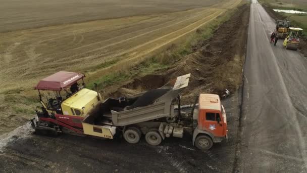 Novosibirská oblast, 3. září2019. Letecký pohled. Naložíme asfaltovou směs do bunkru asfaltové dlažby. Výstavba nové silnice. — Stock video