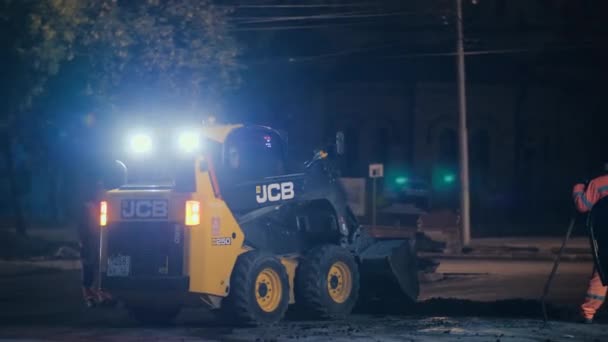 Novosibirsk region, September 7, 2019. The mini loader levels the asphalt mix. Road repair, construction of a new road in the city. Flashing beacons. — Stock Video