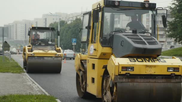Novosibirsk, 7 de septiembre de 2019. Tres rodillos de carretera están colocando el asfalto. Reparación de carreteras en la ciudad en tiempo nublado. — Vídeos de Stock