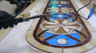 Lehim kaplı cam dikişler. Eldivenli sanatçıların elleri lehim makinesiyle. Lekeli cam atölyesi, el işi. El yapımı.