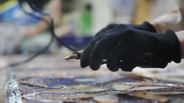 Närbild Lödning färgade glassömmar. Handskar konstnärer händer med en lödkolv. Målat glas verkstad, hantverk. Handgjorda — Stockvideo