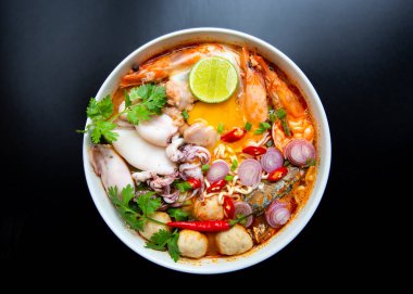 Siyah arka planda beyaz kasede sıcak ve baharatlı şehriye çorbası..