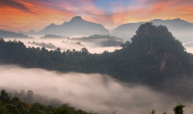 Sabah sislerle kaplı dağ ve güneş doğmadan önce gökyüzünde alacakaranlık ışığı var..