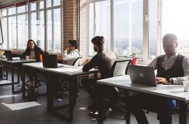 Genç iş adamı modern ofiste bilgisayarla çalışıyor.