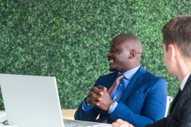 İş elbisesi giymiş Afroamerikan işadamının portresi bir toplantıda masada oturuyor.