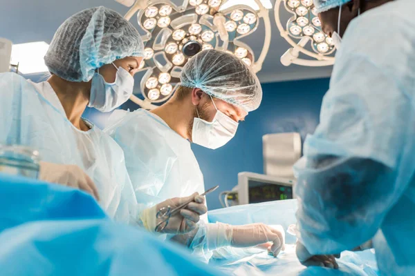 Uluslararası bir doktor ekibi, anestezi altındaki bir hastaya karmaşık bir ameliyat uygular. Modern ameliyathane ve deneyimli cerrahlar hayat kurtarıyor. — Stok fotoğraf