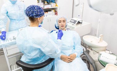 Dişçi konsepti. Profesyonel diş hizmetleri ve acısız modern ekipmanlar. Doktor ve asistanı hastaların dişlerini tedavi ediyor.