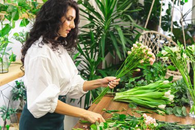 Çekici genç bayan çiçekçi bir çiçekçide çalışıyor..
