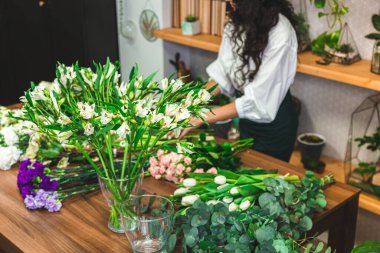 Çekici genç bayan çiçekçi bir çiçekçide çalışıyor..