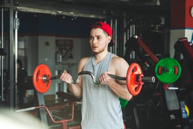Genç aktif kaslı adam spor salonunda halterle egzersiz yapıyor. Güç eğitimi