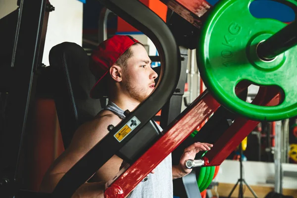 O jovem atleta faz exercícios no ginásio. Abordagens de potência no simulador — Fotografia de Stock