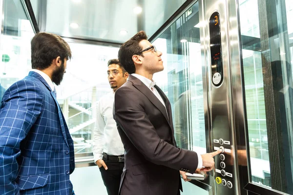 Grupo de negocios en ascensor. Gente de negocios en un gran ascensor de cristal en una oficina moderna. Corporativossteam y gerente en una reunión. — Foto de Stock