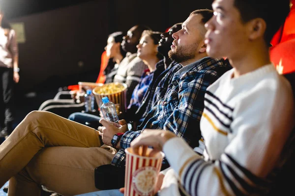 Amigos viendo una película en el cine con palomitas de maíz. La gente se sienta en los sillones del cine y mira la pantalla — Foto de Stock