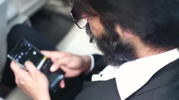 Тихий індійський бізнесмен користується телефоном, сидячи на задньому сидінні автомобіля.. — стокове відео