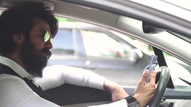 자동차 운전대에 앉아 있는 세련 된 인도 사업가는 비디오 전화를 통해 의사소통을 한다 — 비디오