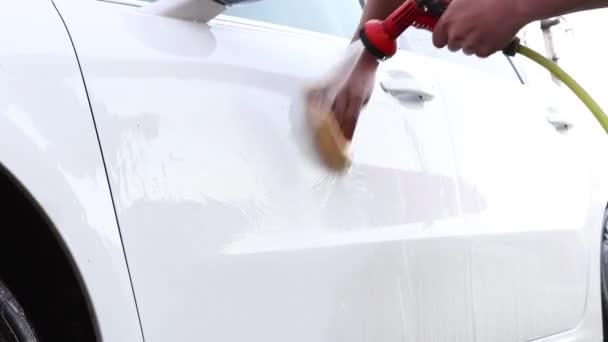 Egy férfi lemossa a kocsiját egy speciális tömlőből. Kézi hordozható autómosó. Részletes és gyengéd autóápolás — Stock videók