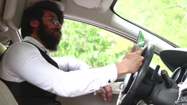 자동차 운전대에 앉아 있는 세련 된 인도 사업가는 비디오 전화를 통해 의사소통을 한다 — 비디오