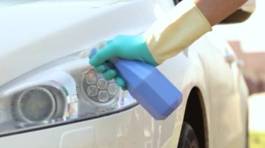 Profesyonel araba temizliği. Eldivenli bir adam kurşunlayıcı ile ışık optiği ve farları bez parçasıyla temizler ve siler.