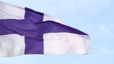 Finlandiya 'nın ulusal bayrağı mavi gökyüzüne karşı rüzgarda dalgalanır.
