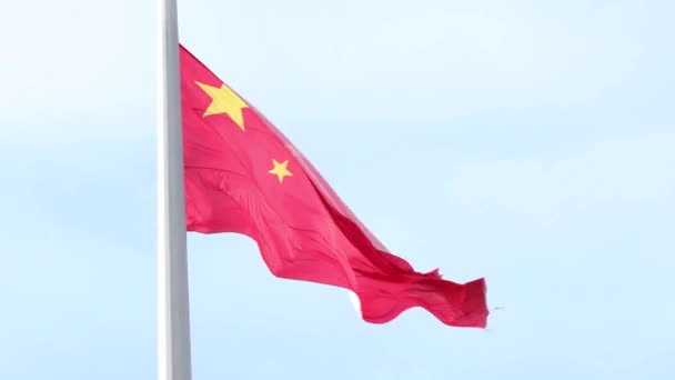 Stora kinesiska nationalstatens flagga viftar i vinden på en flaggstång mot en blå himmel på nära håll — Stockvideo