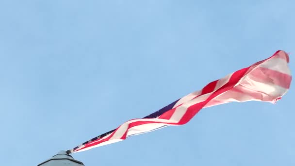 Gran bandera nacional americana ondeando en el viento sobre un asta de la bandera contra un cielo azul de cerca — Vídeos de Stock