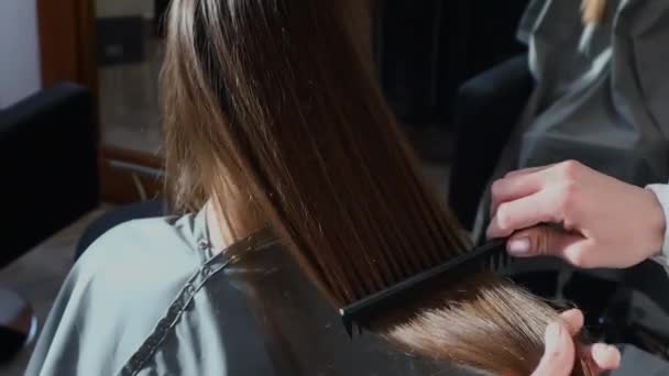 Peluquería de cerca peina el pelo de las niñas por el peinado en un salón de belleza. — Vídeos de Stock