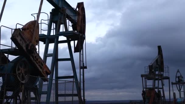 Vor der Kulisse des Abendhimmels arbeiten Saugstangenpumpen und pumpen Öl ab. Ölbrunnenservice — Stockvideo