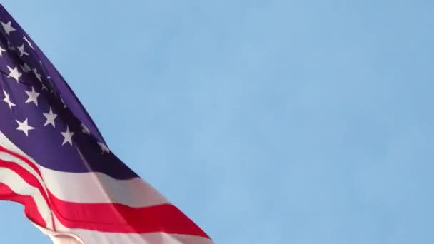 Große amerikanische Nationalflagge weht im Wind an einem Fahnenmast vor blauem Himmel aus nächster Nähe — Stockvideo