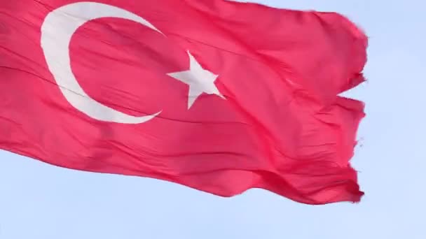 Turkiska nationalstatens flagga viftar i vinden på en flaggstång mot den blå himlen på nära håll — Stockvideo