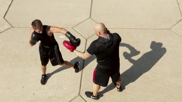 Augusztus 10, 2020 Ufa, Oroszország: Két férfi gyakorol és harcol odakint. A kesztyűs bokszoló edzővel edz. — Stock videók
