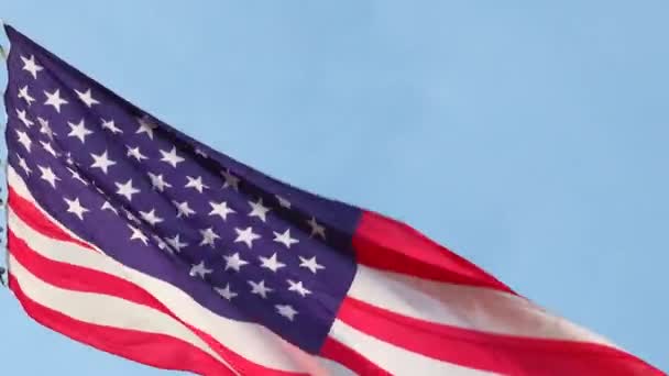 Большой американский национальный государственный флаг, размахивающий на ветру на флагштоке против голубого неба — стоковое видео