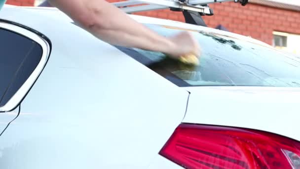 Un hombre lava su sedán con un trapo húmedo especial. .. Cuidado del coche detallado y suave — Vídeo de stock