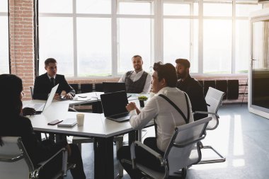 Ofis masasında iş arkadaşlarıyla otururken çalışan ve iletişim kuran bir grup genç iş adamı. iş toplantısı