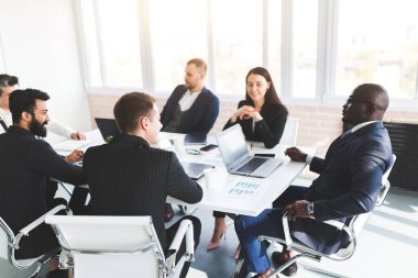 Ofis masasında iş arkadaşlarıyla otururken çalışan ve iletişim kuran bir grup genç iş adamı. iş toplantısı