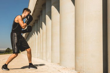 Egzersiz yapan ve dışarıda dövüşen, eldivenli bir boksör. erkek boksör portresi