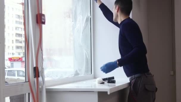 Ein professioneller Fensterputzer seift und drückt ein Fenster sauber, männliche Reinigungskraft. — Stockvideo